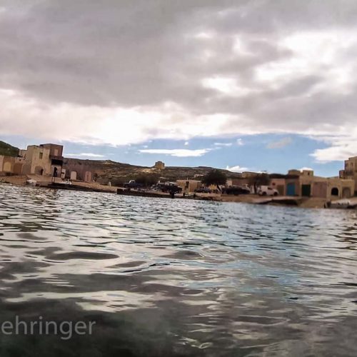 view at inland sea gozo with coulorful boat shelters around the water