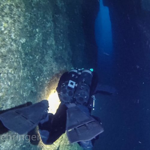diver exiting il baba cave through a crack